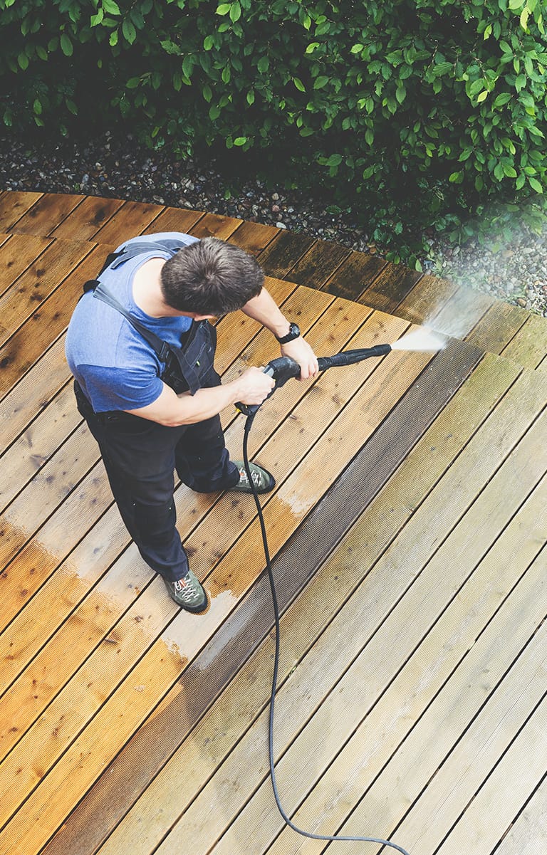 man jet washing patio