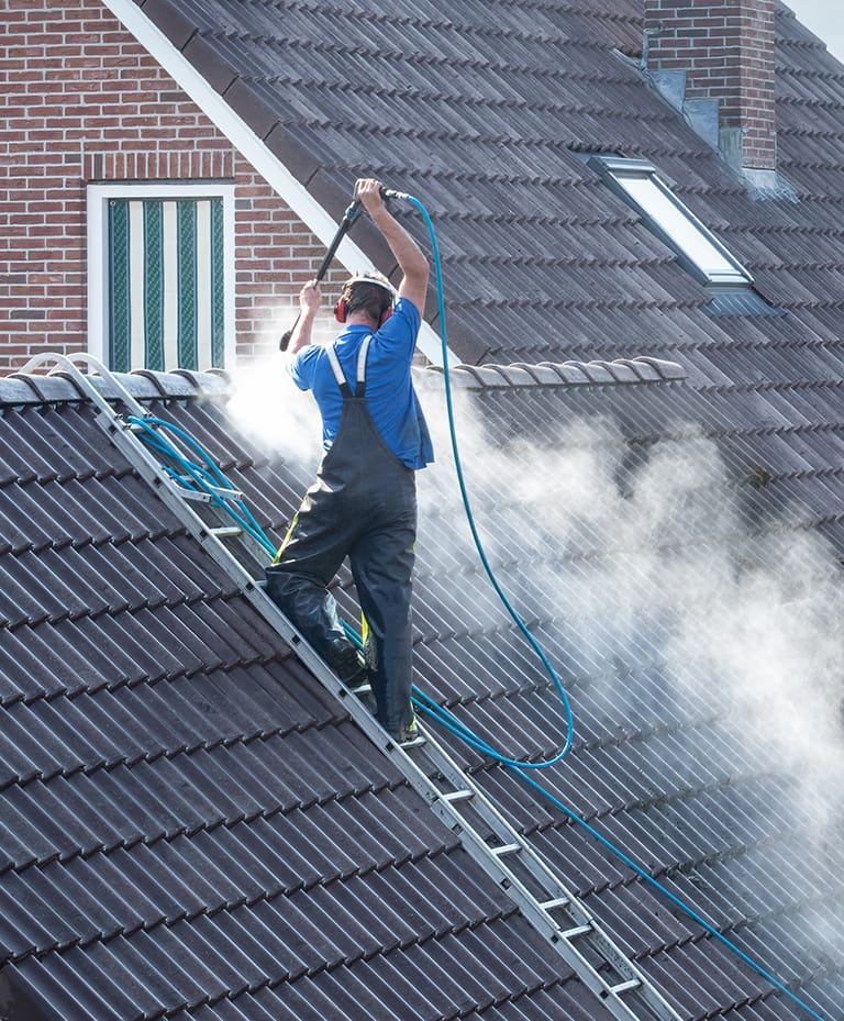 man jet washing a roof